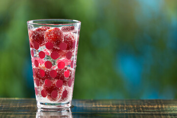 refreshing carbonated summer drink with strawberries in a glass, on a wooden table