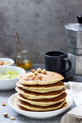 Vegetarian breakfast of pancakes, coffee, honey, nuts and fruits.