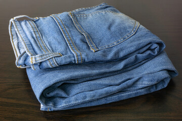 Close up of folded casual cool blue jeans on the wooden table.