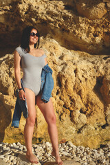 woman standing in a denim jacket on a background of yellow rock