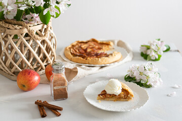 Piece of Baked galette or open pie with apples, cinnamon and ice cream on the table. Pastry, traditional french cuisine recipe. Bakery. Side view, cookbook, restaurant menu