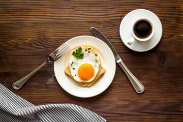 Fried eggs sandwich on plate - dark wooden dinner table top view
