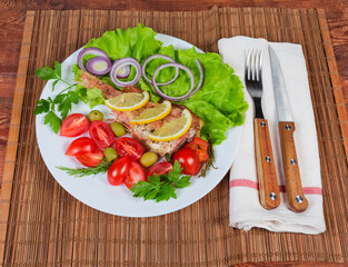 Baked ocean perch on dish, knife and fork on napkin