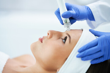 Beautiful young woman getting face treatment at beauty salon.