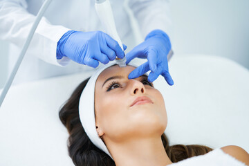 Beautiful young woman getting face treatment at beauty salon.