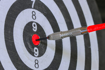 Close up Red Dart arrow hitting in the target center of dartboard for background Target business,...