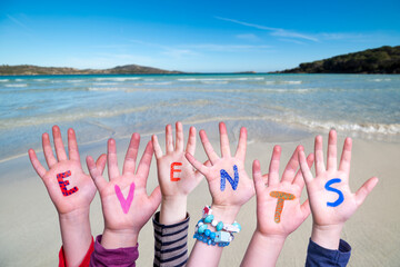 Many Children Hands Building Colorful Word Events. Ocean And Beach As Background