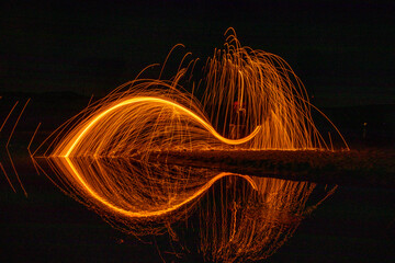Fish image and reflection that emerged with steel wool work at night time.