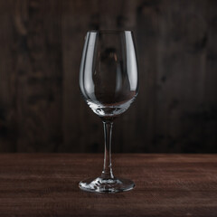 Empty wine glass on wooden table against dark background in bar. Catering Concept