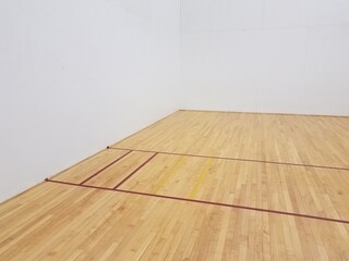 red tape on wooden floor with white walls in racquetball court