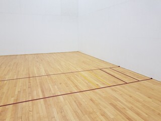 red tape on wooden floor with white walls in racquetball court