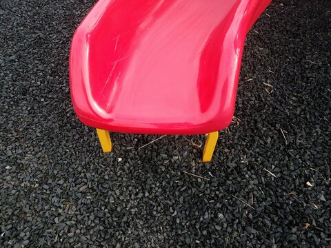 red plastic slide with yellow metal and grey shredded recycled car tires