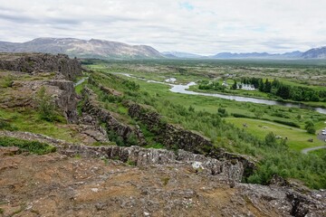 Fototapeta na wymiar Landscape with Oxara river near Thingvallavatn lake with rocky range in Thingvellir, Iceland in overcast weather