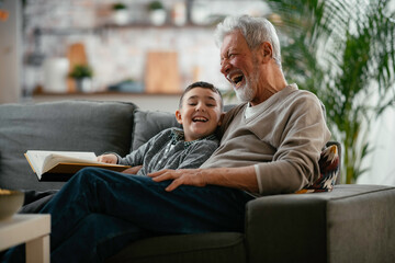 Grandfather and grandson reading a book. Grandpa and grandson enjoying at home.	