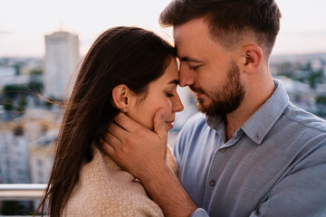 Close up portrait, man and woman smiling to each other on sunset with city in background. Couple romantic intimate moments