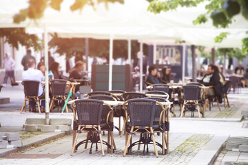 Reastaurant tables waiting for customers at an outdoor terrace.