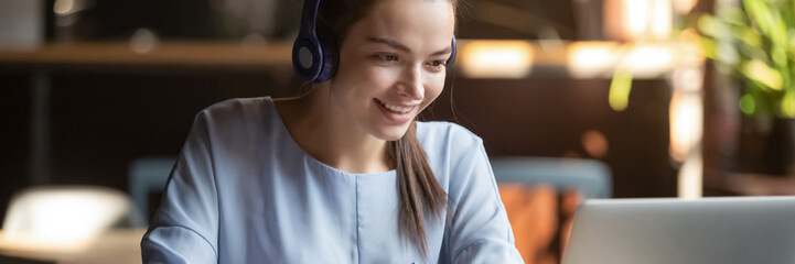 Woman wear headphones look at pc enjoy study online with tutor, listen audio lecture watch webinar prepare for exams, e-learn, self education concept. Horizontal photo banner for website header design
