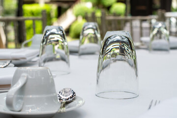 A glass of clear water is upside down on the dining table covered with elegant white cloth.