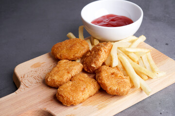 Nugget, french fries plating on wood chopping board
