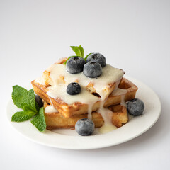 fresh square waffles with sauce, blueberries and mint leaves