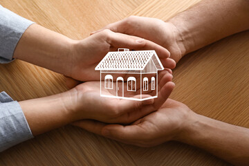 Home security concept. Couple holding house indoors, closeup