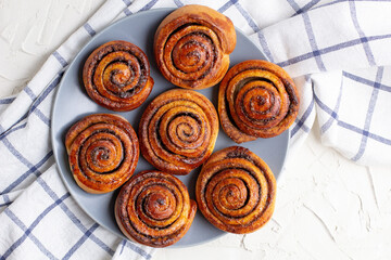 baked cinnamon buns on grey plate on light background with checkered napkin