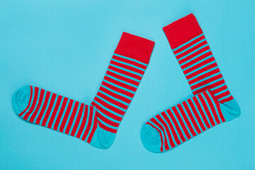 a pair of socks in red and turquoise stripes, as if striding, on a turquoise background