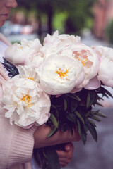 A bouquet of peonies in the hands of a woman