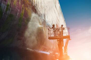 Worker Washing and Cleaning with cargo ship at side shell in floating dry dock with water jet  from...