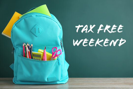 Backpack with school stationery and text TAX FREE WEEKEND written on chalkboard in classroom