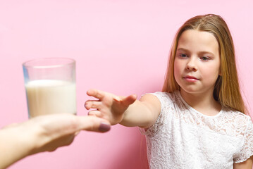 girl with pigtails and milk mustache drinks milk on pink background.