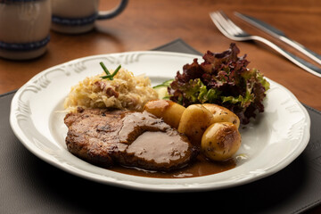 rib eye steak with spaetzle salad on leather mat and wooden table