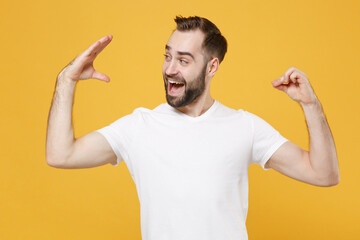 Excited young bearded man guy 20s in white casual t-shirt posing isolated on yellow background studio portrait. People lifestyle concept. Mock up copy space. Showing blah blah gesture ja jaja hands. © ViDi Studio