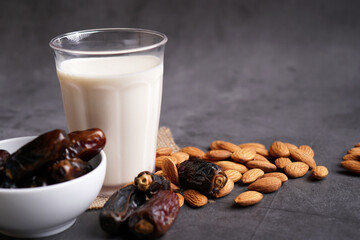 A glass of almond milk on a rusty surface, with almonds and dates in the background. Copy space for text flatlay. Badam and dates.
