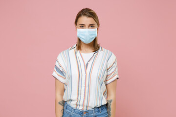 Young blonde woman girl in casual striped shirt sterile face mask isolated on pink background. Epidemic pandemic rapidly spreading coronavirus 2019-ncov sars covid-19 flu virus concept Looking camera.