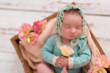 Newborn girl, baby boy sleeping in a basket with pink garden flowers.