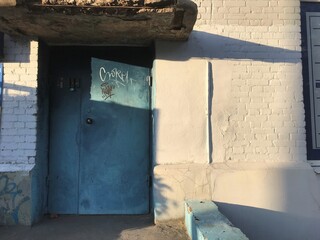 old blue metal doors and a white brick wall with shadows at sunset