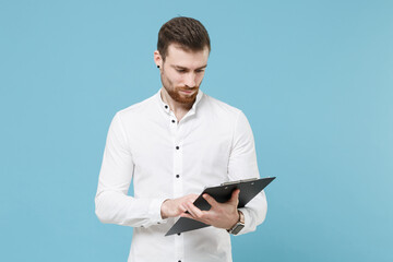 Naklejka na ściany i meble Handsome young bearded man guy 20s in white classic shirt isolated on pastel blue wall background studio portrait. People lifestyle concept. Mock up copy space. Hold clipboard with papers document.