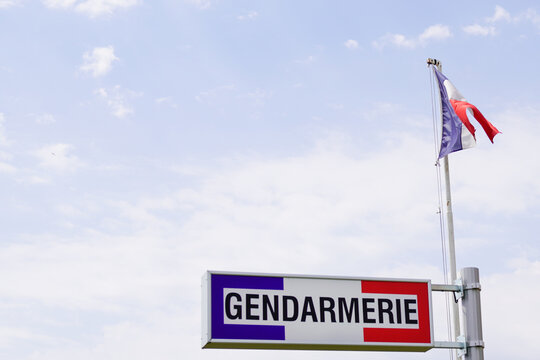 Gendarmerie french military police sign and french flag in cloudy sky