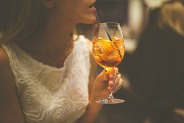 Girl drinking spritz aperol. Woman holding glass with orange coctail. Evening chill in bar or restaurant.