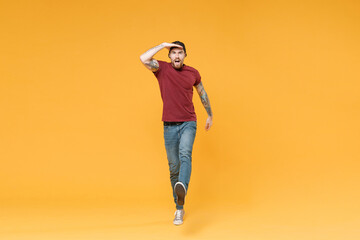 Fototapeta na wymiar Shocked young bearded tattooed man guy in casual t-shirt black cap posing isolated on yellow background. People lifestyle concept. Mock up copy space. Hold hand at forehead looking far away distance.