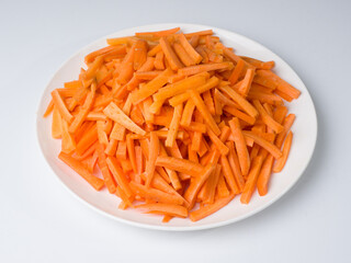 Sliced carrots on a white plate. Preparing an ingredient for a national Central Asian pilaf dish. Traditional cuisine
