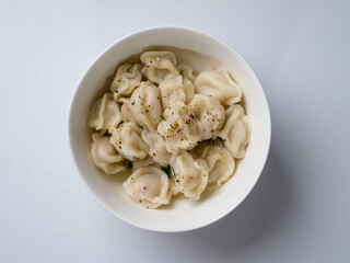 Russian dumplings in the broth. White round bowl on a white background
