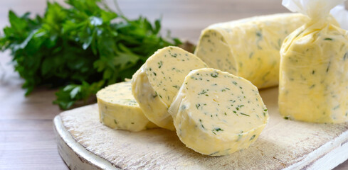 Butter with a herb for sandwiches and steak. Portion of Herb Butter sliced on a wooden board. Homemade italian food. Selective focus.