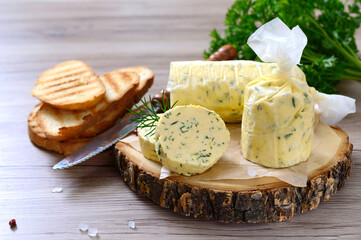 Butter with a herb for sandwiches and steak. Portion of Herb Butter sliced on a wooden board. Homemade italian food.