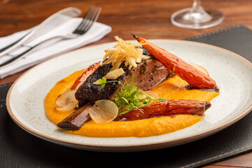 sliced rib garnished with vegetables over mashed potatoes on a white plate