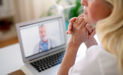 Senior woman with laptop at home, consulting doctor and video call concept.