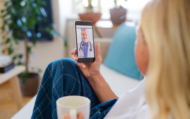 Senior woman with smartphone at home, consulting doctor and video call concept.