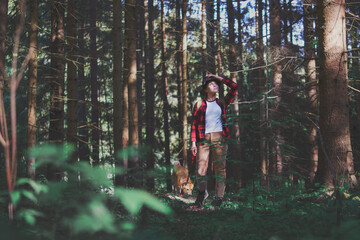 Young woman with a dog on a walk outdoors in forest in summer nature.