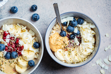 Oatmeal bowl with banana, berries, hemp seeds and coconut slices, top view. Healthy vegan breakfast concept.